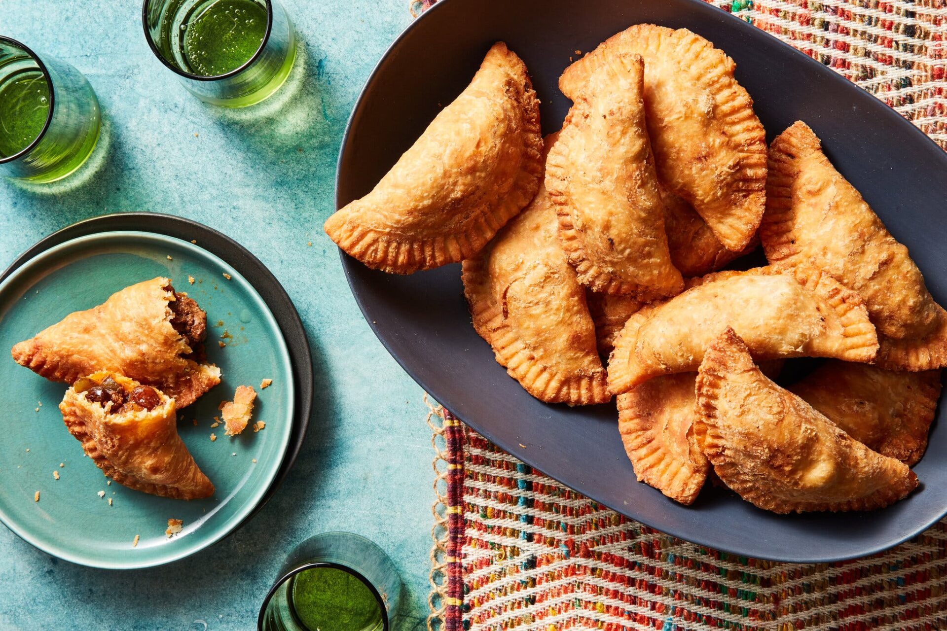 An overhead image of a platter of empanadas. A single split empanada sits to the side.