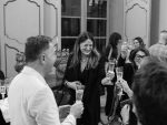 In questa foto, alcune persone sorridenti brindano con calici di vino bianco durante un momento conviviale e rilassato. L’atmosfera elegante e l’ambiente storico rievocano lo spirito dell’iniziativa Palermo for Wedding, che celebra la città come destinazione per eventi indimenticabili.