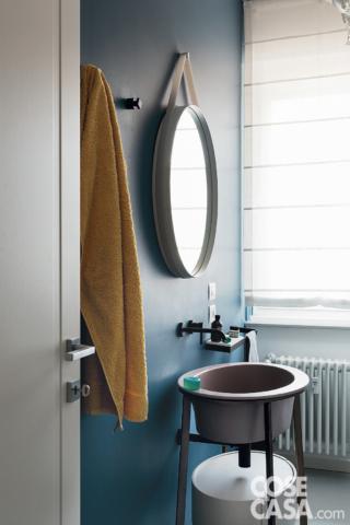 Nel bagno degli ospiti, accessibile dal disimpegno, la parete è impermeabilizzata da un trattamento in resina opaca di colore blu; in resina anche il rivestimento a terra. Il lavabo freestanding fa parte della serie I Catini di Ceramica Cielo; la rubinetteria a parete è della collezione Nostromo di Fantini. Specchio tondo modello Strap di Hay. I prodotti appoggiati sulla mensola sono di Aesop.