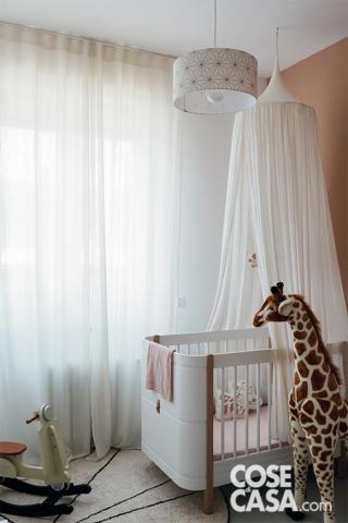 Nella camera del bambino, il lettino con tenda è della serie Wood di Oliver Furniture. La lampada a sospensione è di Fabuleuse Factory, la giraffa di peluche di Childhome.
