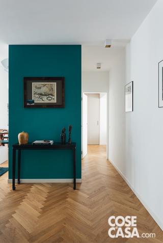 Nell'ingresso la consolle è un modello di modernariato; la parete retrostante è tinteggiata con idropittura. A terra, il parquetè un rovere prefinito con listelli posati a spina di pesce.