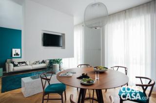 L'area living è illuminata da due portefinestre; sulla porzione di parete tra le due luci è installato un radiatore d'arredo (Charleston di Zehnder) che arriva quasi a tutt'altezza: collegato all'impianto centralizzato, riscalda il soggiorno. In primo piano, il pranzo è integrato nella cucina, mentre oltre la parete c'è la zona conversazione.